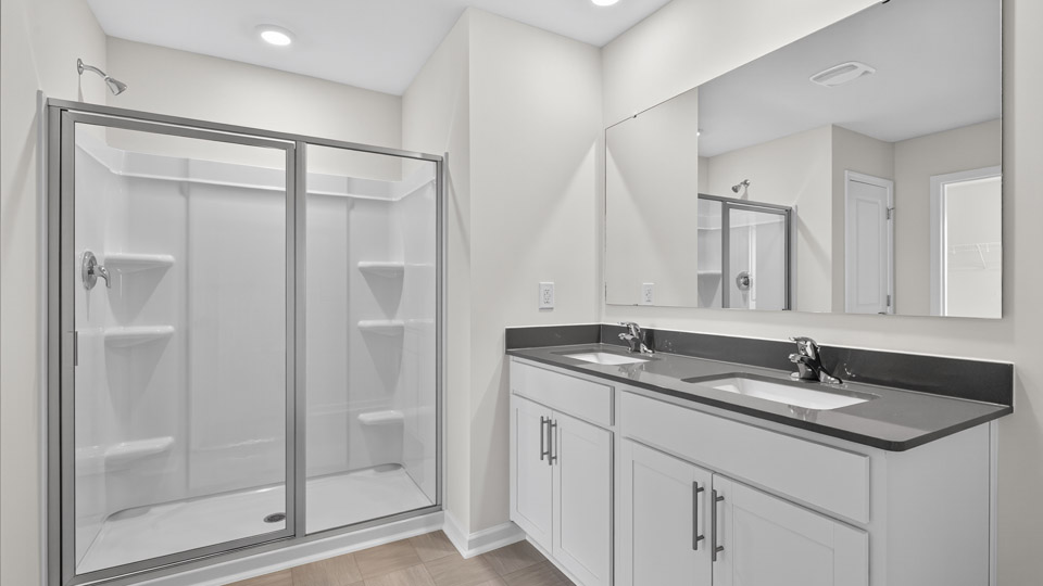 primary bathroom with walk in shower and dual vanity sinks