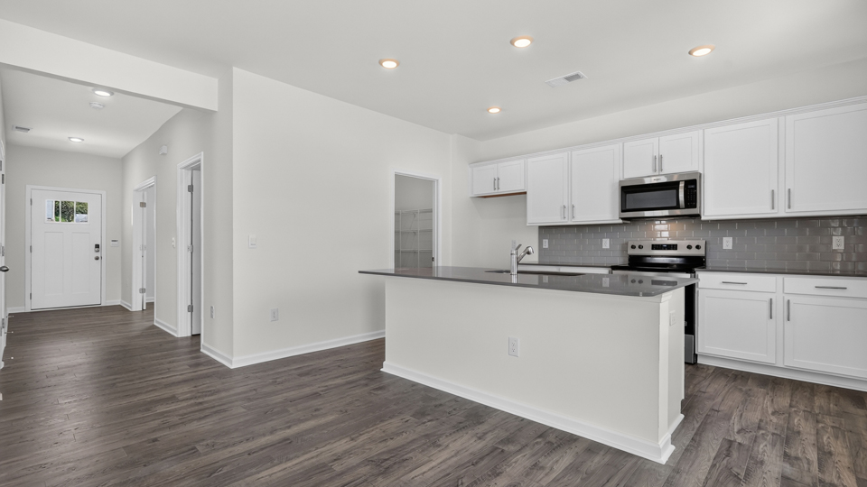 kitchen with quartz counters, kitchen island, pantry, stainless steel appliances