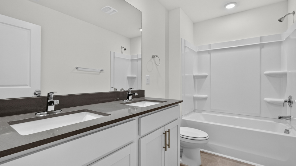 secondary bathroom with shower tub combo and dual vanity sink