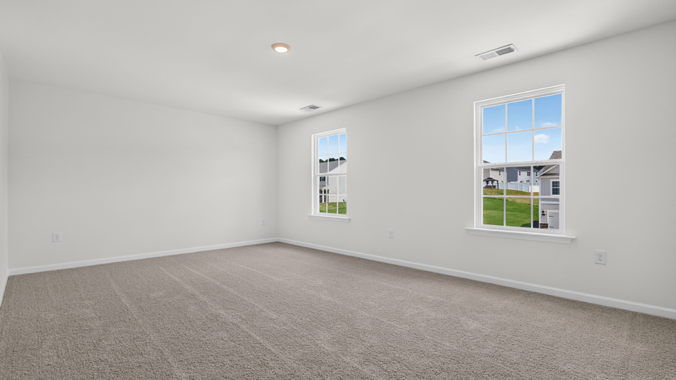 primary bedroom with two windows and carpeting, attached bath