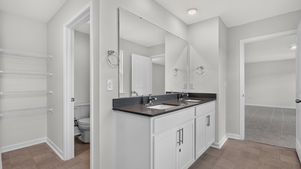 primary bathroom with walk in shower and dual vanity sinks