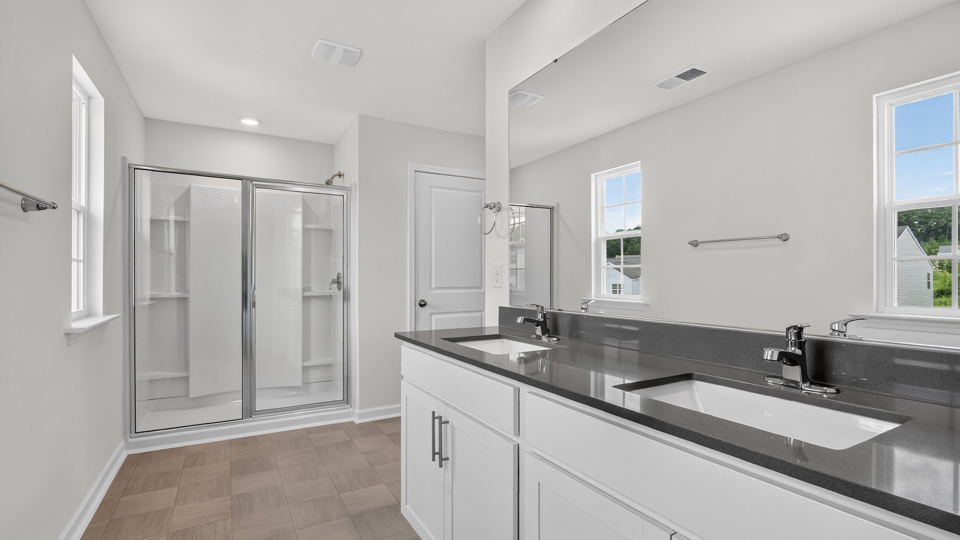 primary bathroom with walk in shower and dual vanity sinks