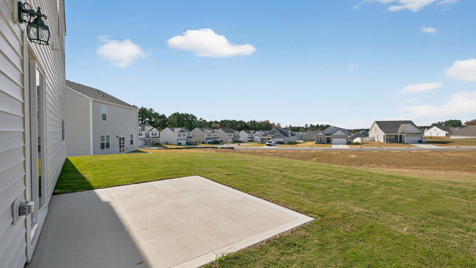 Two story home with white siding and back patio.
