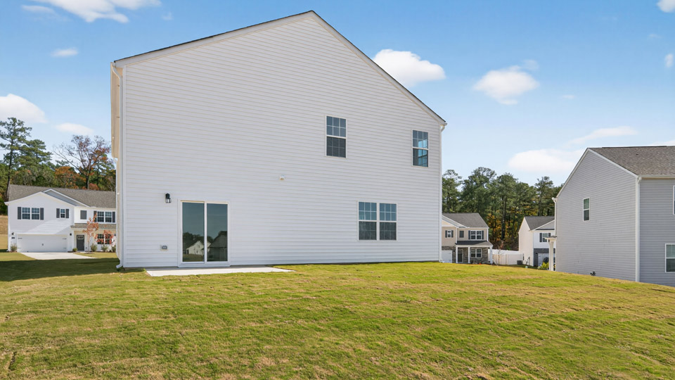 Two story home with white siding and back patio.