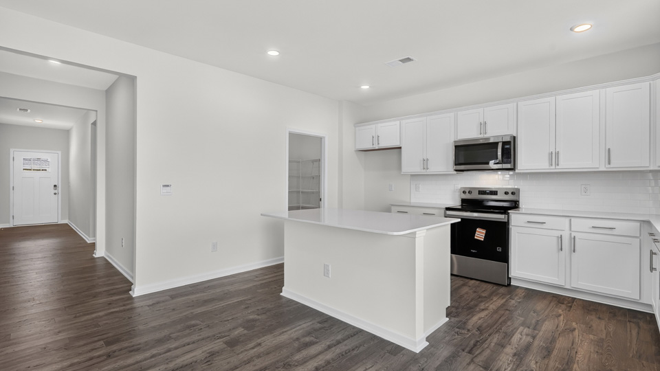 kitchen with quartz counters, kitchen island, pantry, stainless steel appliances