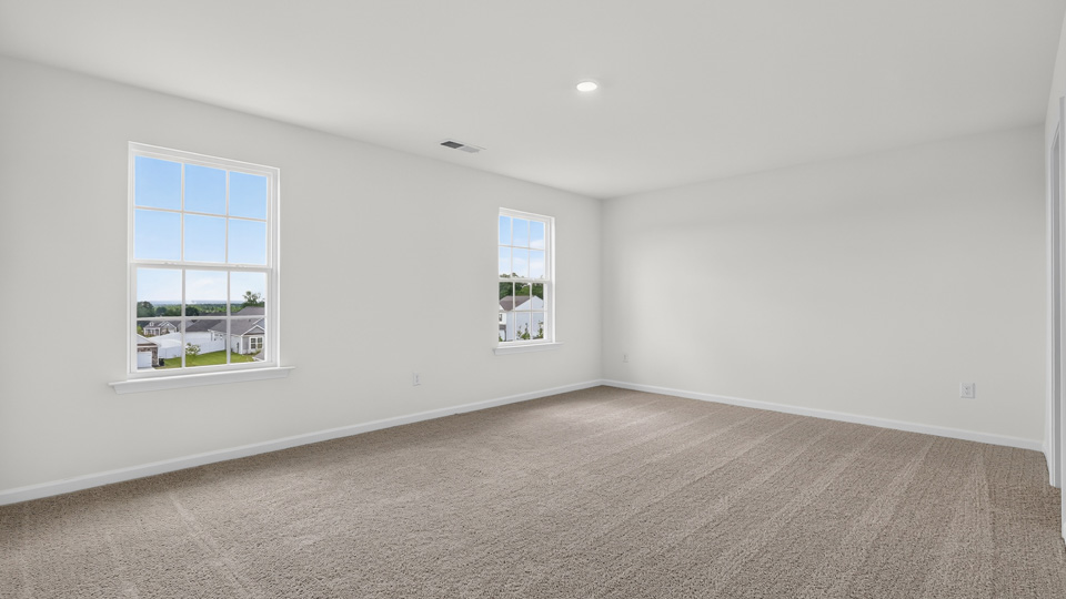 primary bedroom with two windows and carpeting, attached bath