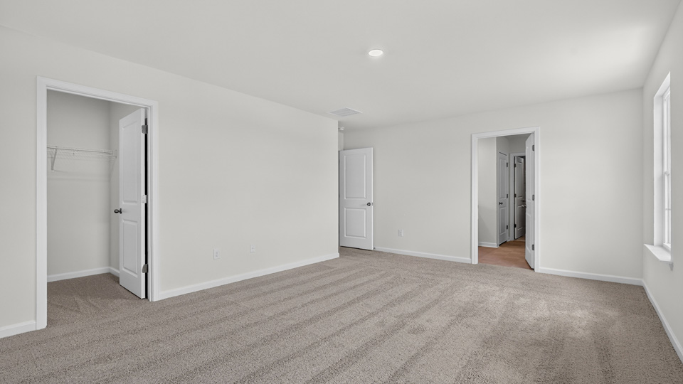 primary bedroom with two windows and carpeting, attached bath