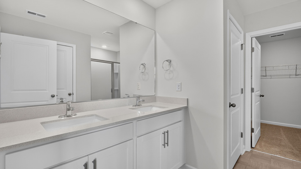 primary bathroom with walk in shower and dual vanity sinks