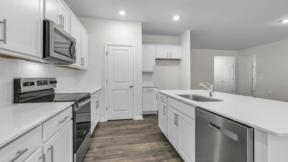 kitchen with quartz counters, kitchen island, pantry, stainless steel appliances