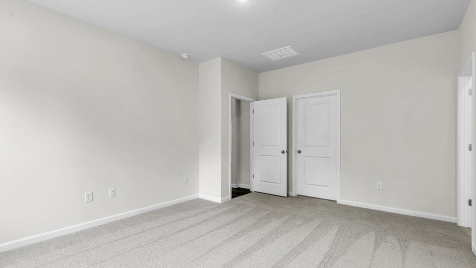 primary bedroom with two windows and carpeting, attached bath