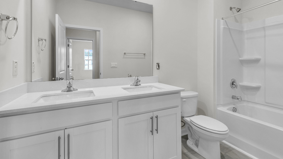 secondary bathroom with shower tub combo and dual vanity sink