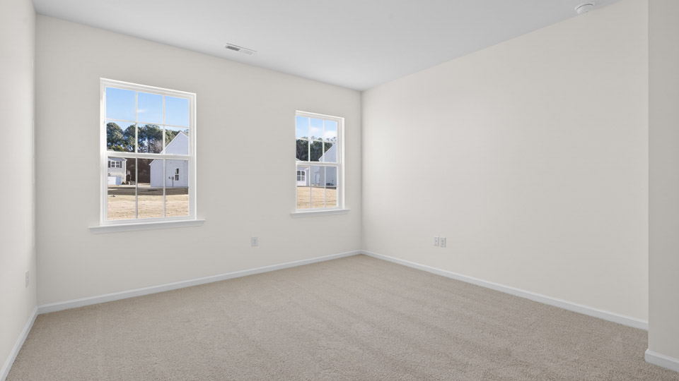 Primary bedroom with carpet floors and windows with access to the primary bathroom