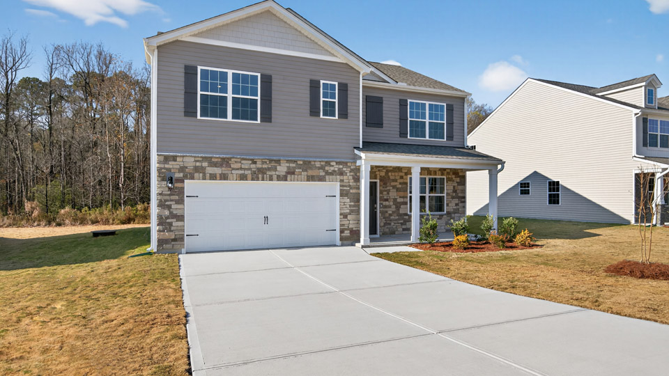 Two story home with gray siding and covered porch and two-car garage.