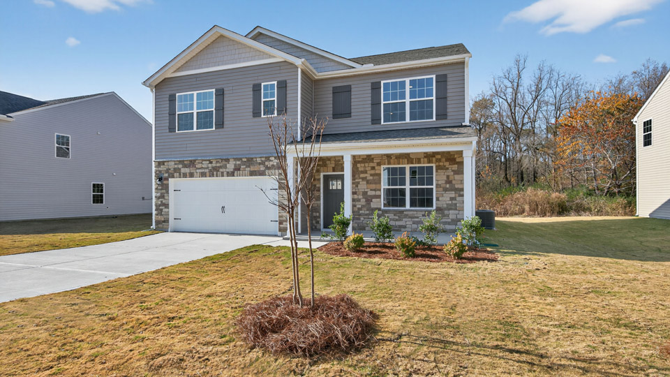 Two story home with gray siding and covered porch and two-car garage.