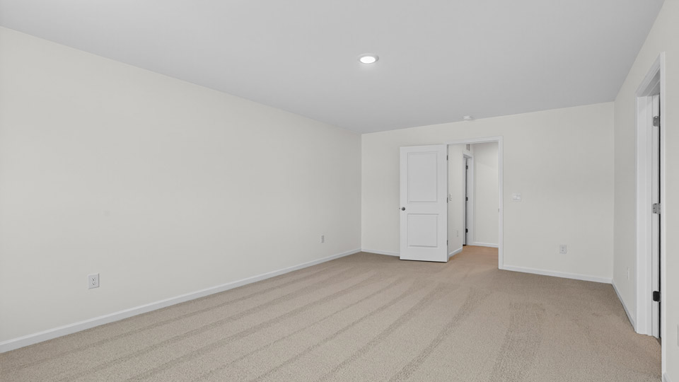 Primary bedroom with carpet floors and windows with access to the primary bathroom