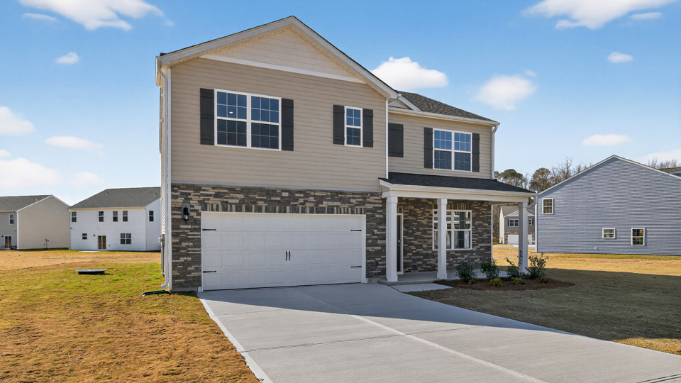 Two story home with yellow siding and covered porch and two-car garage