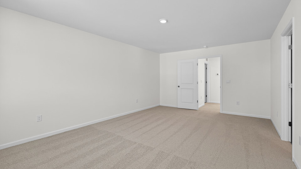 Primary bedroom with carpet floors and windows with access to the primary bathroom