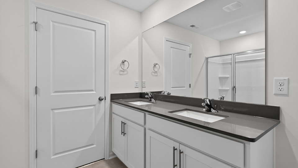 primary bathroom with walk in shower and dual vanity sinks