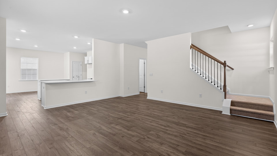 Open-concept living room leading to kitchen and upstairs