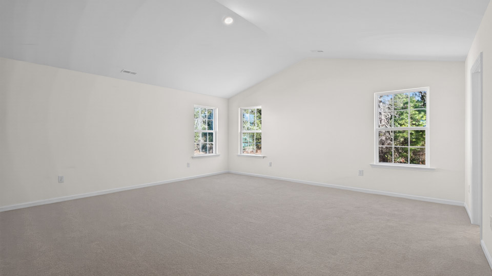 Primary bedroom with carpet floors and windows with access to the primary bathroom