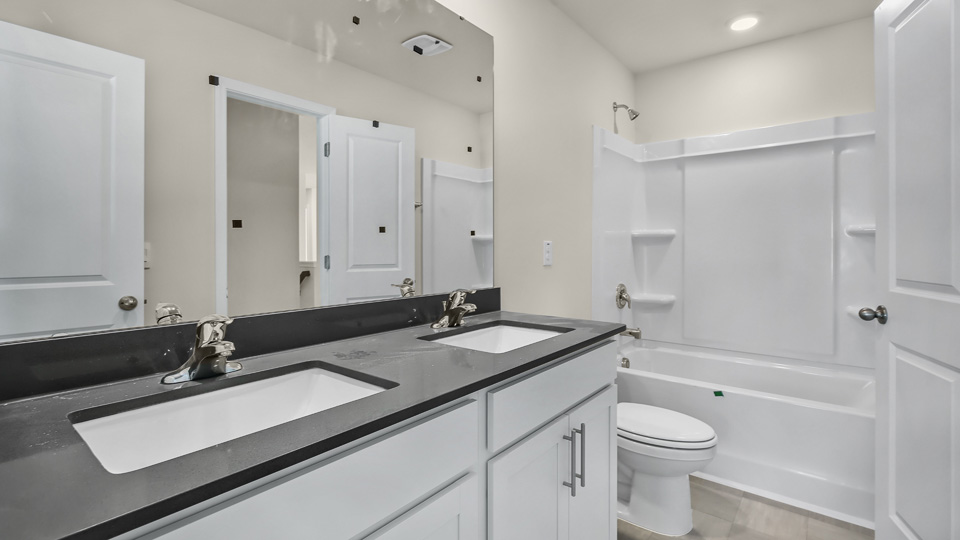 secondary bathroom with shower tub combo and dual vanity sink