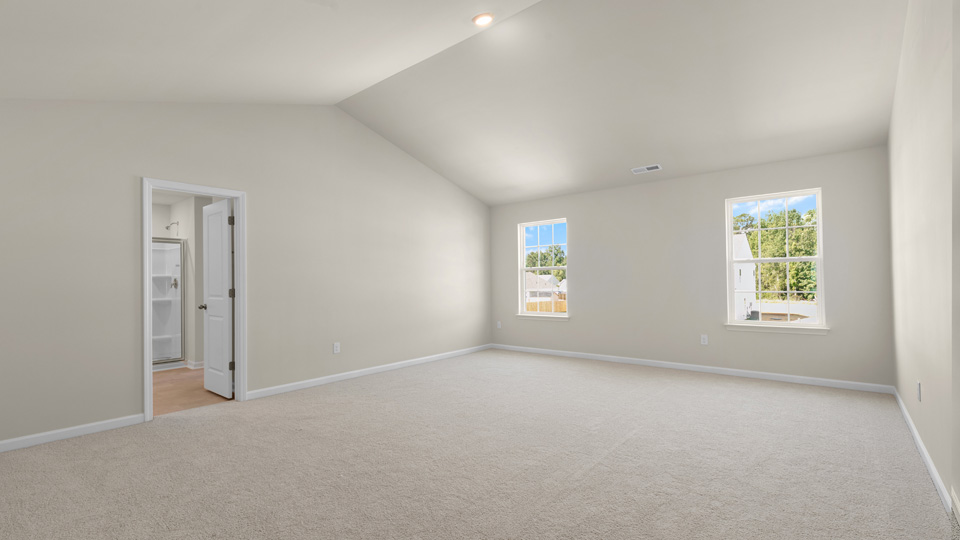 primary bedroom with two windows and carpeting, attached bath