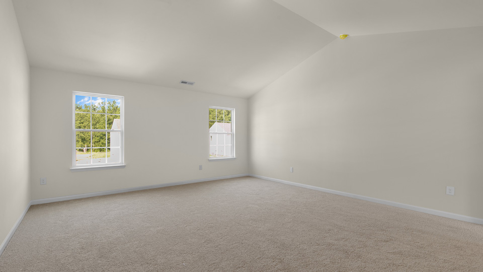 primary bedroom with two windows and carpeting, attached bath