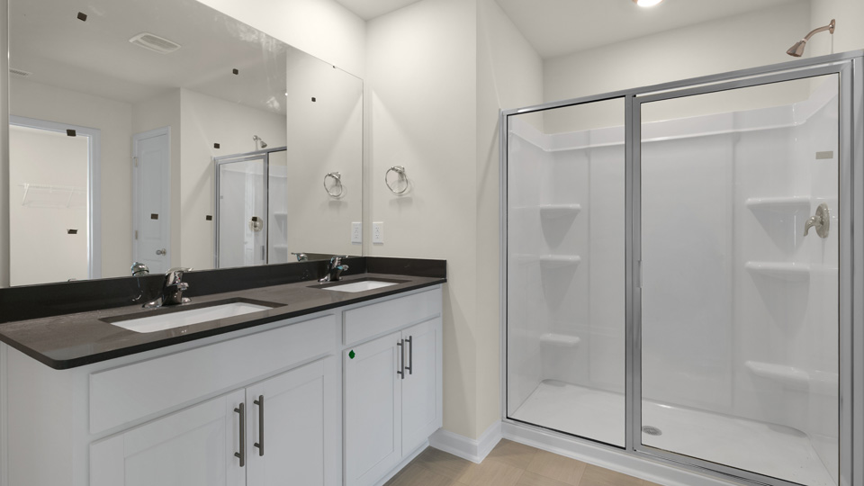primary bathroom with walk in shower and dual vanity sinks