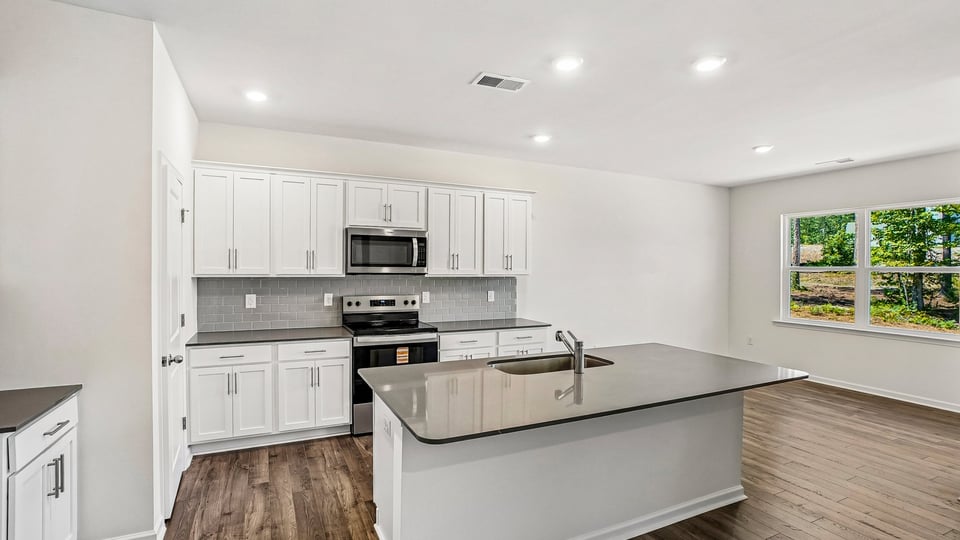 kitchen with quartz counters, kitchen island, pantry, stainless steel appliances