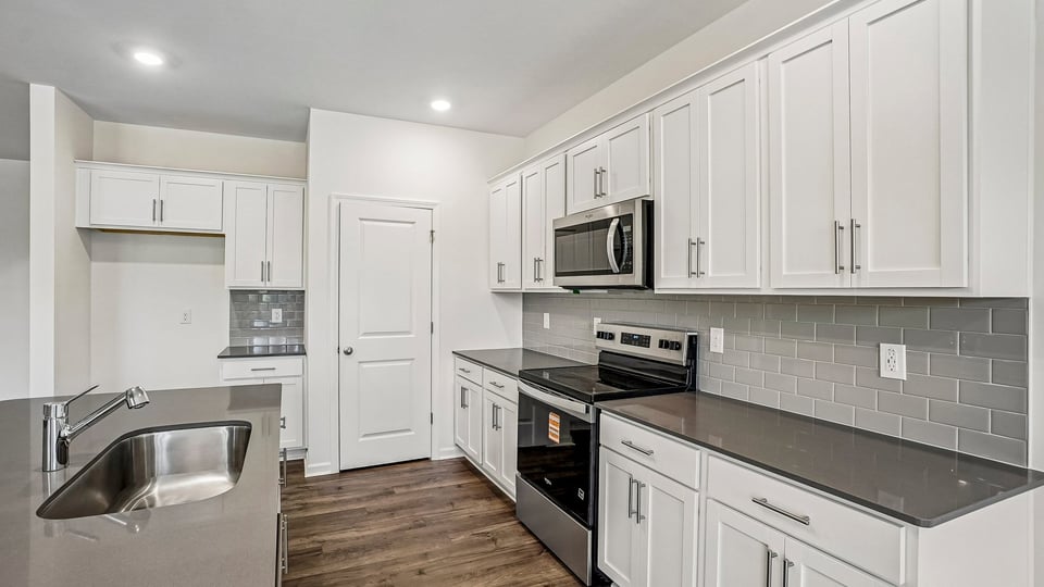 kitchen with quartz counters, kitchen island, pantry, stainless steel appliances