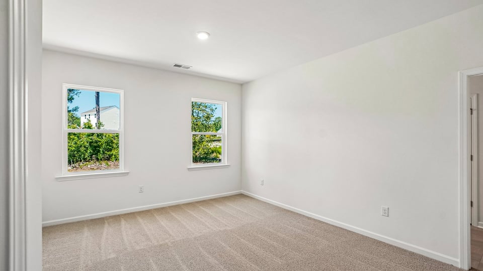 primary bedroom with two windows and carpeting, attached bath