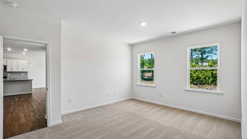 primary bedroom with two windows and carpeting, attached bath
