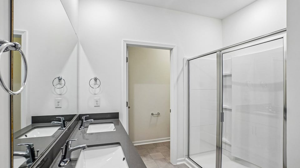 primary bathroom with walk in shower and dual vanity sinks