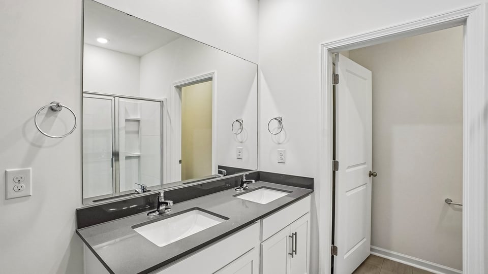 primary bathroom with walk in shower and dual vanity sinks
