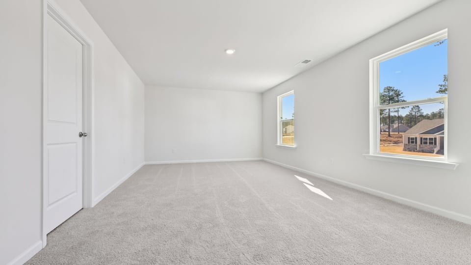 primary bedroom with two windows and carpeting, attached bath