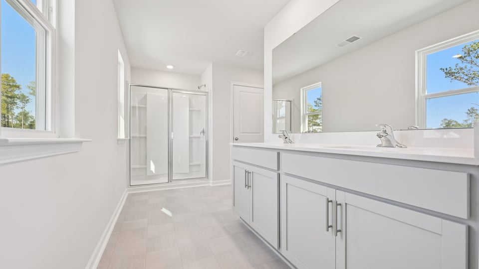 primary bathroom with walk in shower and dual vanity sinks