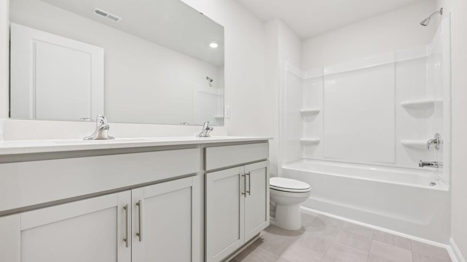 bathroom with tub shower combo and gray cabinets