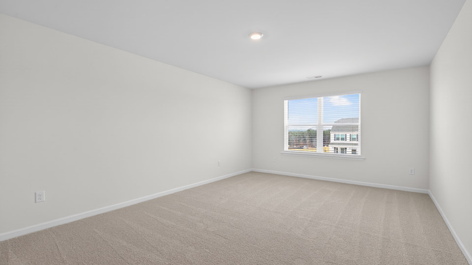primary bedroom with two windows and carpeting, attached bath