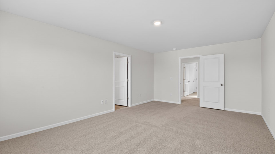 primary bedroom with two windows and carpeting, attached bath