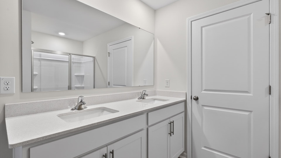 primary bathroom with walk in shower and dual vanity sinks