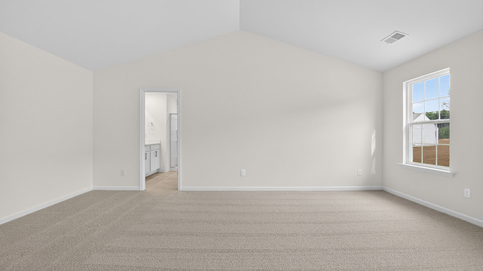 primary bedroom with two windows and carpeting, attached bath