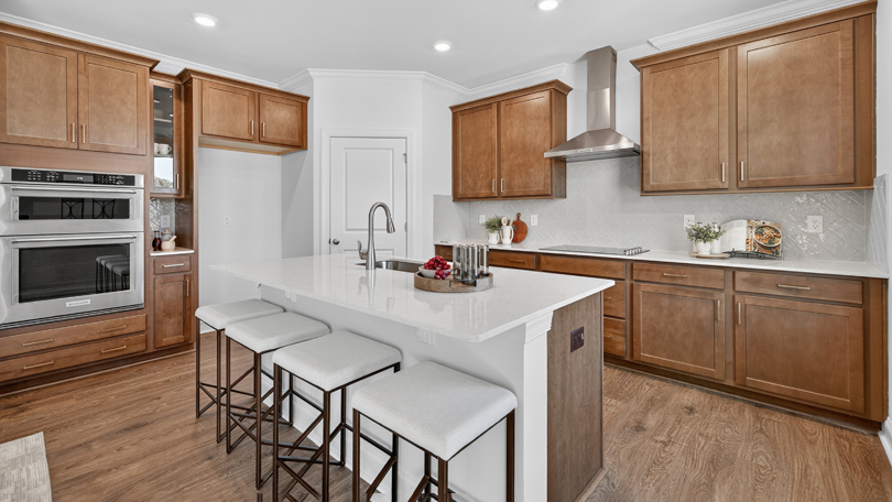 kitchen with brown cabinets quartz countertops tile backsplash and stainless steel appliances