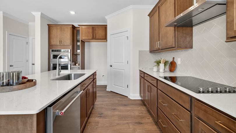 kitchen with brown cabinets quartz countertops tile backsplash and stainless steel appliances