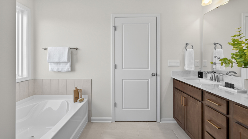 bathroom with separate tub and shower and brown cabinets with quartz countertops