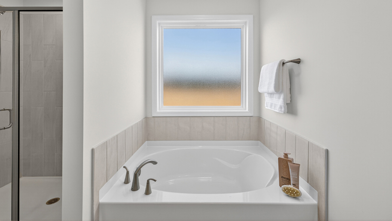 separate tub and shower with window above bathtub