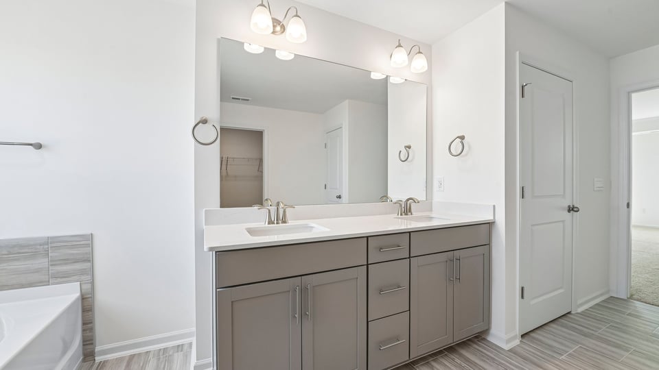 primary bathroom with dual vanity quartz countertops and gray cabinets