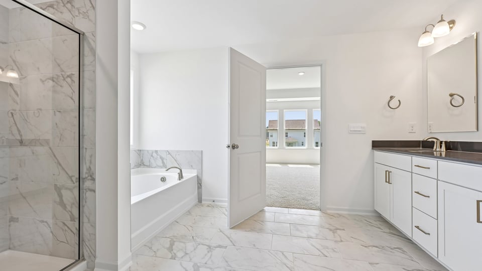primary bathroom with dual vanity and separate tub and walkin shower