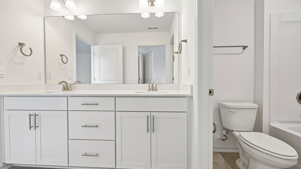 bathroom with white cabinets and dual vanity
