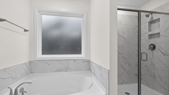 primary bathroom with separate tub and shower with glass doors