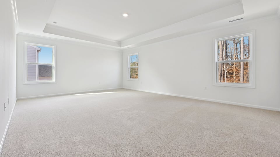 primary bedroom with two windows and carpeting, attached bath